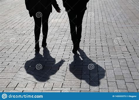 Silhouettes And Shadows Of Two Women Walking Down The Street Stock