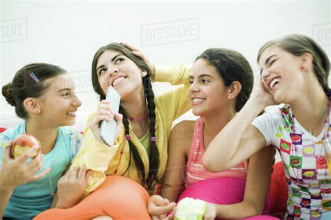 Four Young Female Friends Sitting Together Smiling Snacking Stock