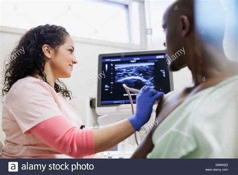 Female Technologist Performing Ultrasound On Male Patients Shoulder In