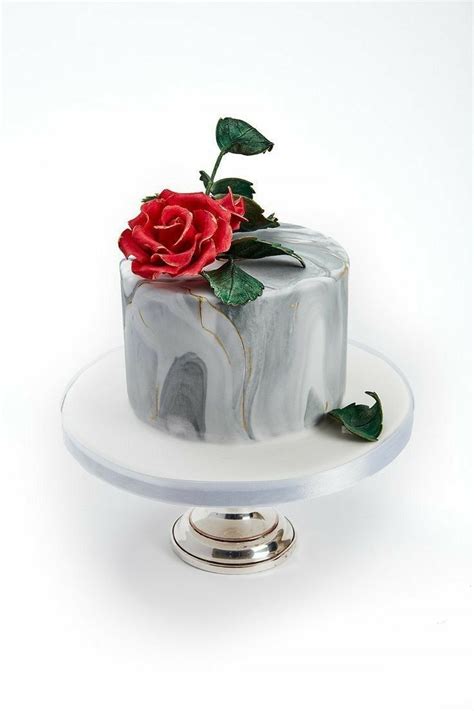 A Marble Cake With A Red Rose On Top Is Sitting On A White Platter