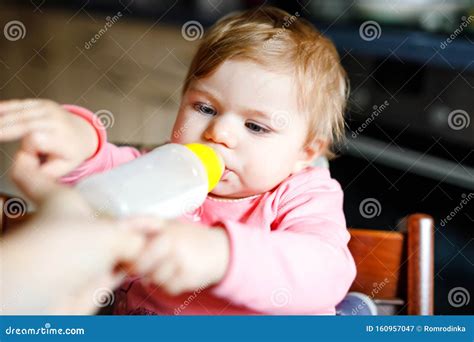 Cute Adorable Baby Girl Holding Nursing Bottle And Drinking Formula