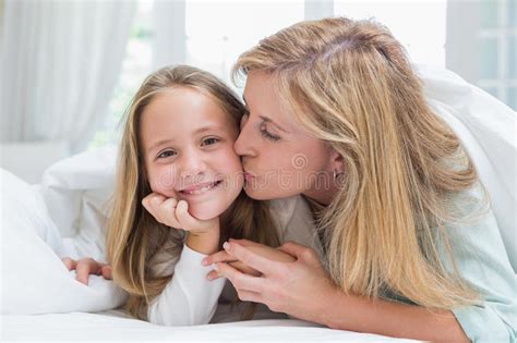 Mother Kissing Her Daughter On The Cheek In The Bed Stock Image Image
