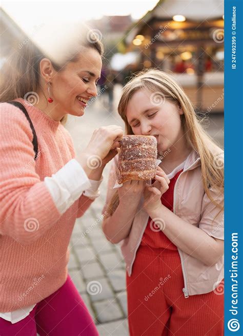 Happy Modern Mother And Child At Fair In City Eating Trdelnik Stock