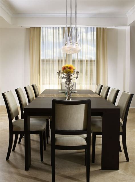 A Dining Room Table With Chairs And A Vase Filled With Flowers