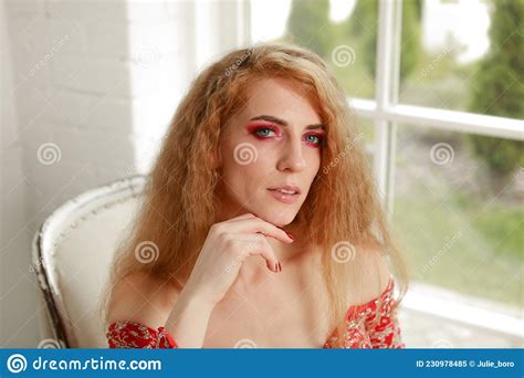Red Haired Woman With Bright Makeup And In A Red Evening Dress Stock
