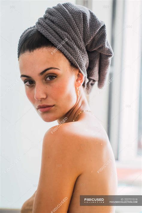 Portrait Of Young Topless Woman With Towel On Head Turning Around And Looking At Camera