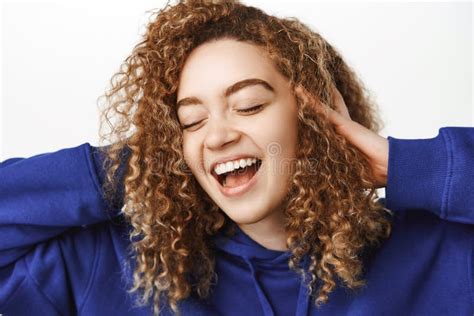 close up portrait of carefree beautiful woman with healthy curly hair smiling and touching