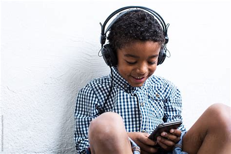 Little Boy Listening Music Whilst Using Smartphone By Stocksy