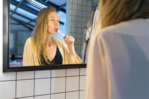 Beautiful Young Woman Looking Into Bathroom Mirror Brushing Her Teeth