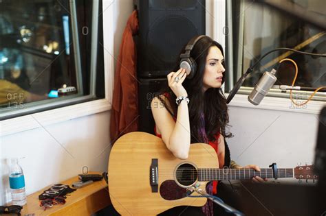 Young Woman Playing Acoustic Guitar At A Recording Studio Stock Photo