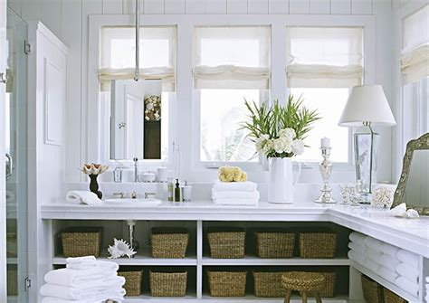 Beautiful bathroom with white corner dual vanity paired with polished nickel hardware, undermount sinks, traditional style faucets along with upper cabinets flanking frameless. L Shaped Vanity - Cottage - bathroom - Jackie Lanham