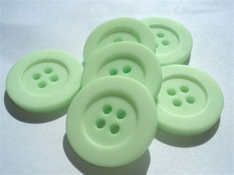 Five Green Buttons Sitting On Top Of A White Surface
