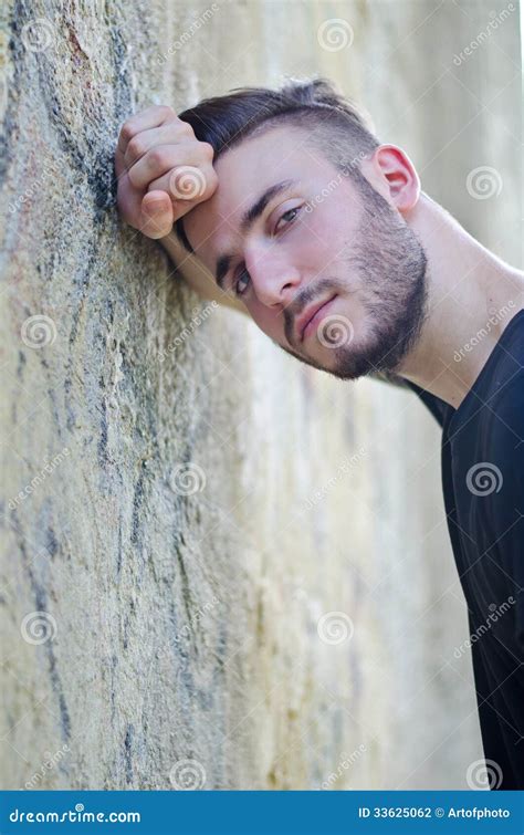 Attractive Young Man Leaning His Head Against Arm On A Wall Stock Photo
