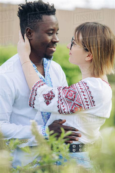 Interracial Couple Embraces In Spring Garden Dressed In Ukrainian Traditional Ethnic Embroidered
