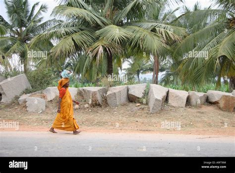 a indian woman walks down the street carrying her belongings on her head in hampi northern