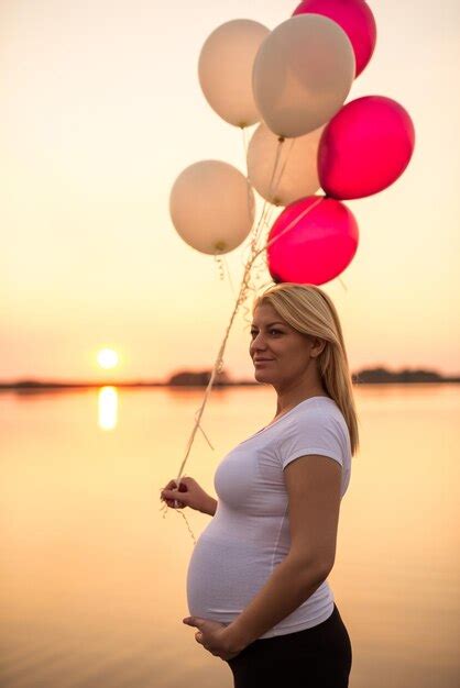 Premium Photo Pregnant Woman Holding Her Belly And Balloons On A Sunset