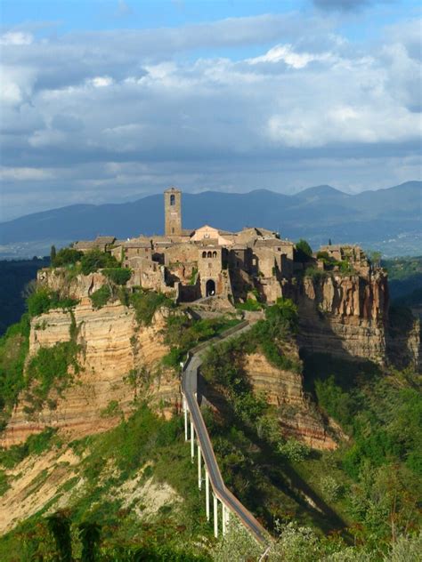 An Old Castle Perched On Top Of A Mountain With A Road Going Up Its Side