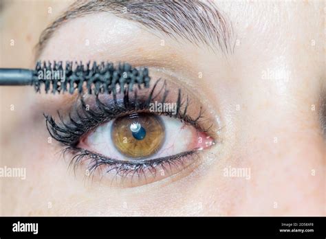 Close Up Of The Eye Of A Young Woman Putting On Makeup With Mascara For