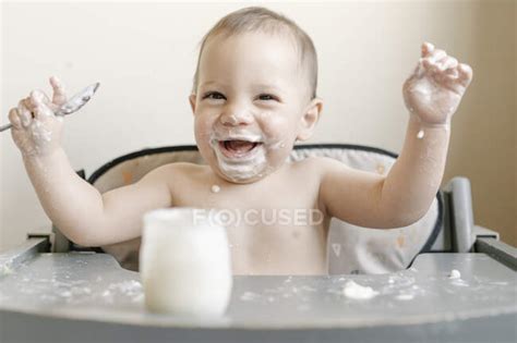 Little Baby Boy Eating Yogurt In Highchair At Home — One Person Babies