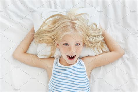 Top View Of Cheerful Little Girl With Blonde Hair Feckles And Blue