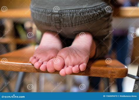 Child Is Sitting On Chair In Room Legs And Feet Of Kids Stock Image