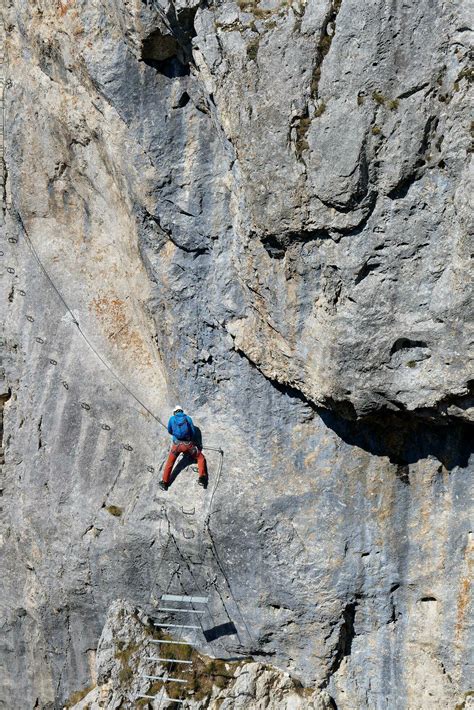 A Person Climbing A Via Ferrata Route On A Vertical Rock Wall Sports