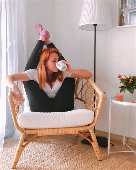 a woman sitting in a wicker chair drinking from a cup with her legs up
