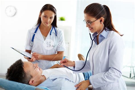 Portrait Of Two Female Doctors Looking At Patient During Medical