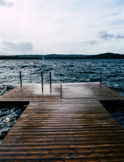 Brown Wooden Dock Viewing Blue Sea And Mountain Under White And Blue