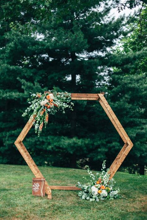 A Bright Hexagon Wedding Arch Decorated With Greenery White And Orange