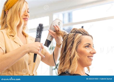 Hairdresser Drying The Hair Of A Blonde Woman In Her Hair Salon Stock
