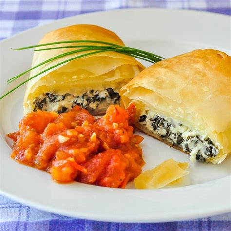 A White Plate Topped With Two Pastries Covered In Sauce