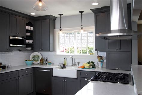 Polished white kitchen with gray wall tiles, dark blue breakfast island, white enamel cabinets with gold handles, hardwood floor, and pendant lights. Miraculous White Kitchen with Grey Walls — Modern Design