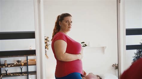 Upset Overweight Woman Looking At Her Reflection In Mirror Disappointed With Body Condition