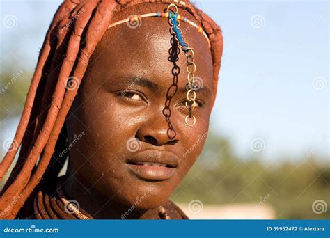 Portrait Of A Himba Girl Looking After The Goat Herd Carrying A Baby On