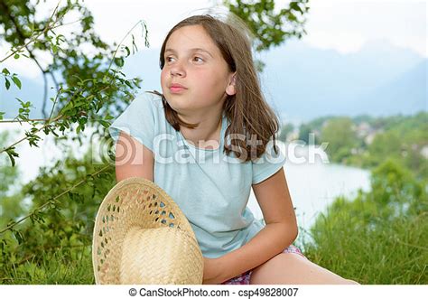 A Pre Teen Girl Sitting In Grass Lake In Background Canstock