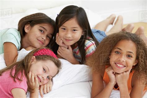 Group Of Young Girls Lying On Bed Stock Photo Dissolve
