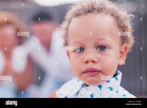 Mixed Race Boy With Blue Eyes Looking At Camera And Parents On Back