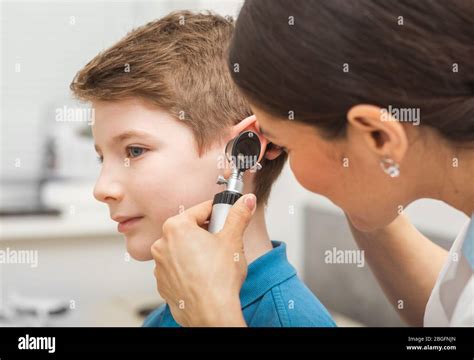 Doctor Examining Boy Ear Using Otoscope In Doctors Office Child