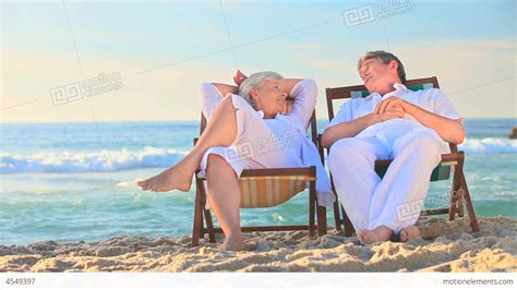 Elderly Couple Sitting In Deckchairs On A Beach Stock Video Footage