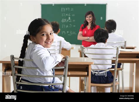 Schoolgirl Looking Back Towards Camera And Teacher With Her Classmates