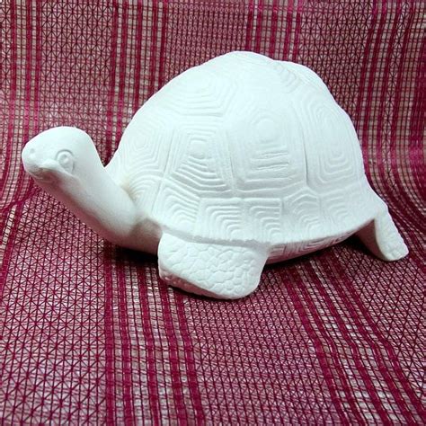A White Turtle Figurine Sitting On Top Of A Red Checkered Cloth