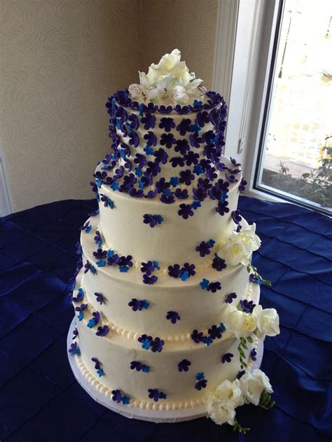 A Three Tiered Wedding Cake With Blue And White Flowers On The Side In