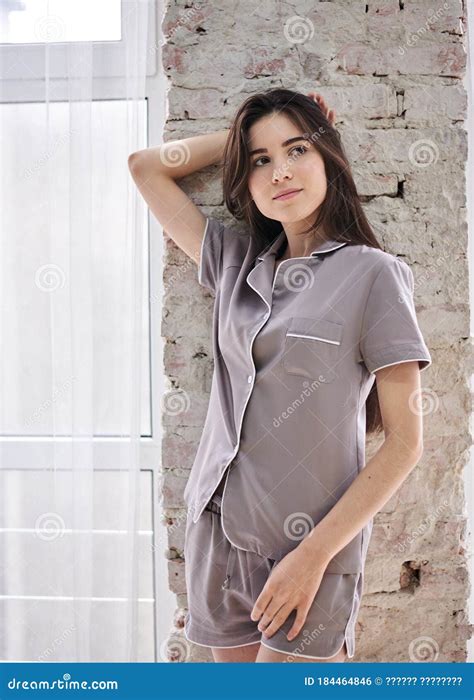Young Pretty Slim Brunette Woman Wearing Grey Satin Pajamas Posing