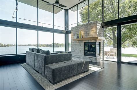Modern house near water on bright day. Glass Lake House Features Modern Silhouette of Earthy ...