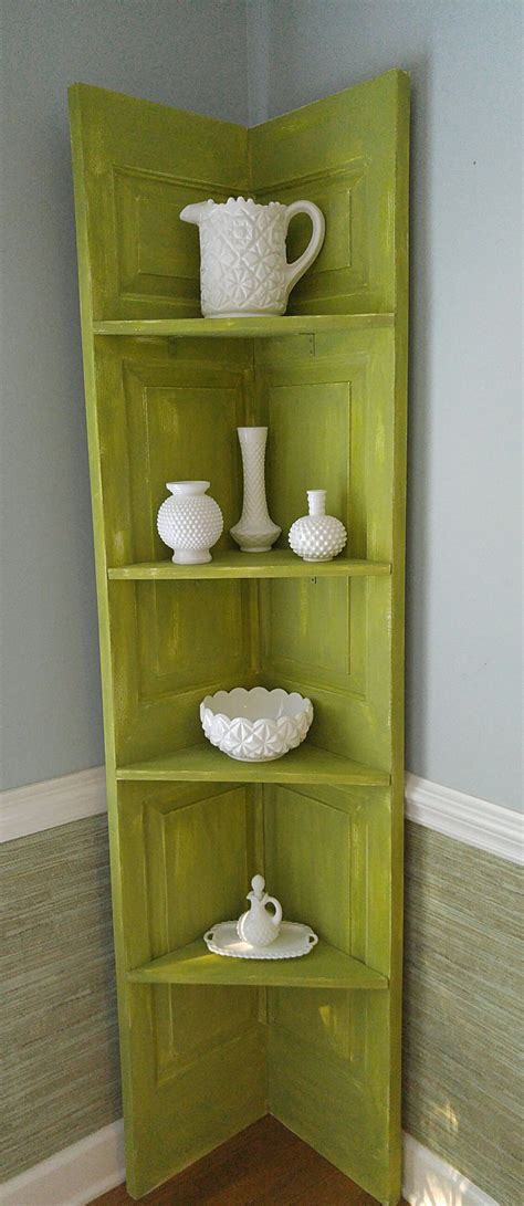 A Green Corner Shelf With White Dishes On It