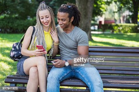 Jeune Couple Interracial Assis Dans Le Parc Et La Navigation Sur Leurs