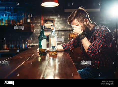 Alcoholic Sitting At The Bar Counter And Drinks Strong Alcohol