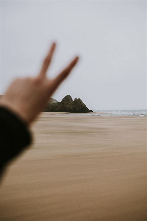 persona mostrando izquierda mano mar océano arena viajar playa