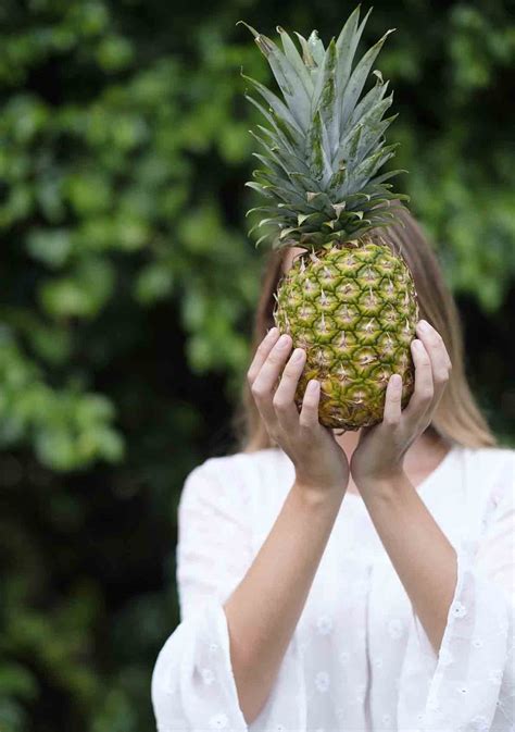 Woman Holding Pineapple In Front Of Face In Park